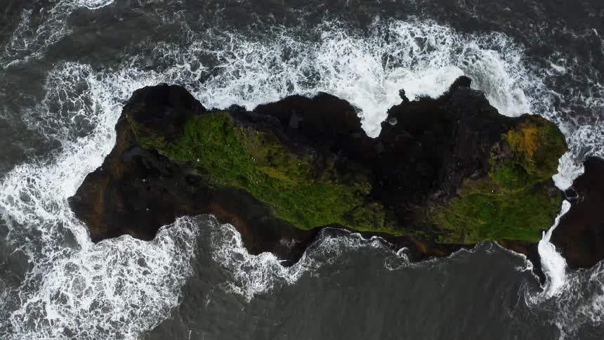 Aerial view of ocean waves breaking against sea stacks