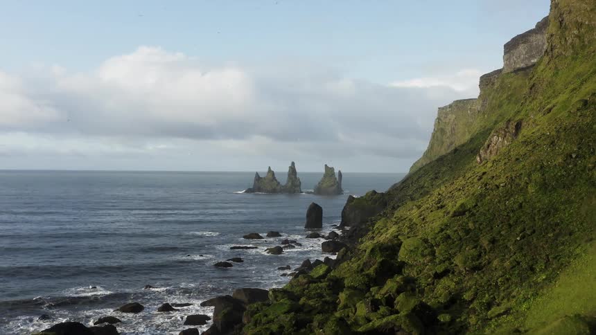 A rocky coast with water and waves with the sky and clouds in the background