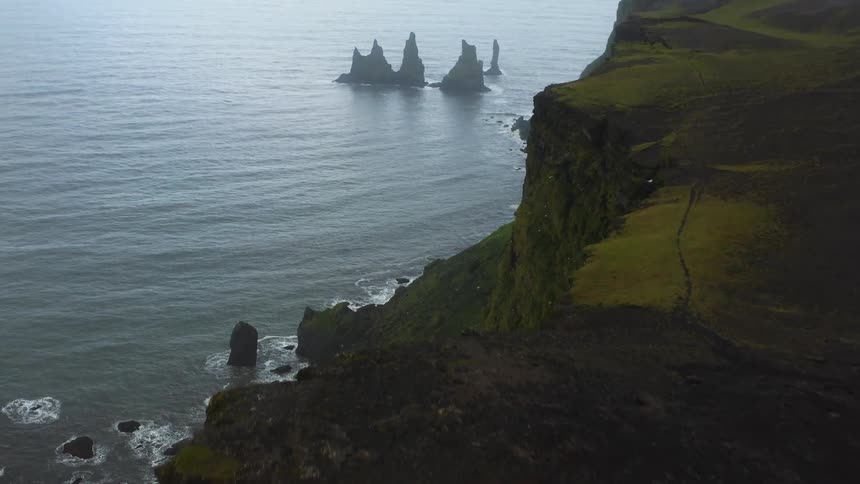 View from over a cliff of rock formations in the water along a coastline