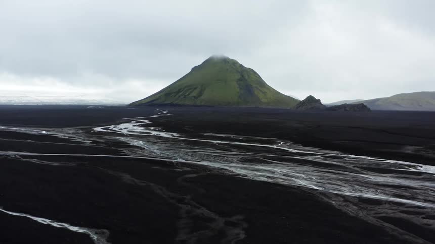A river and several small creeks weave around a volcano