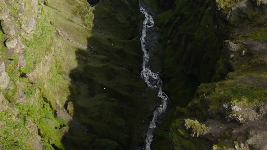A river between two cliffs with birds flying in the sky