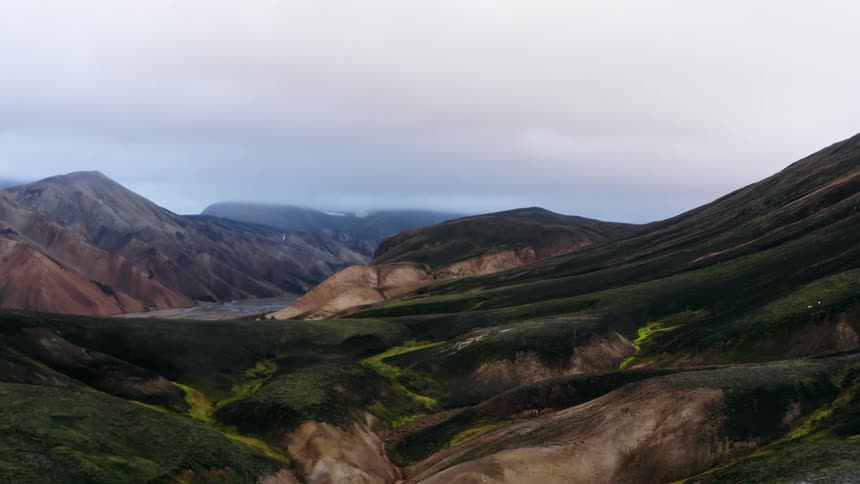 Hill and mountain terrain leads to valley with misty plateau on the horizon