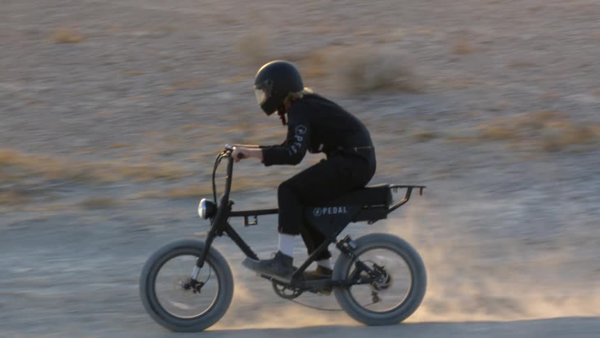 A woman rides a dirt bike offroad during the day