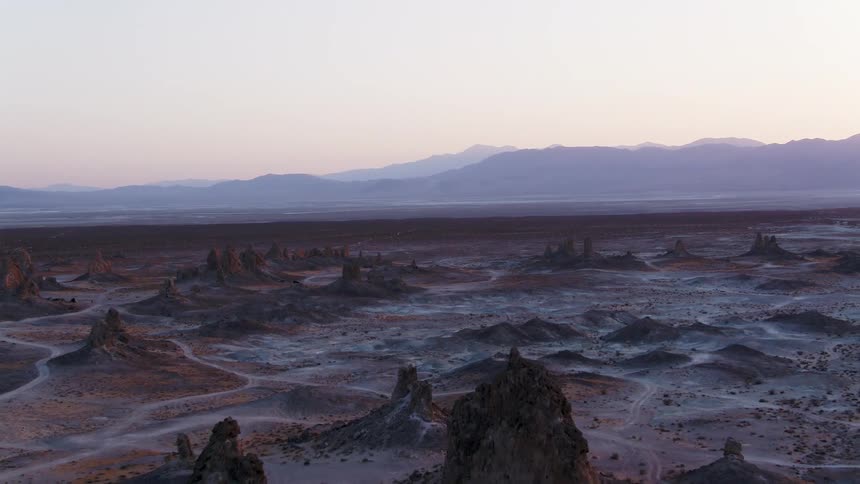 Aerial view of the rock promontoires on the badlands near the mountains at sunset