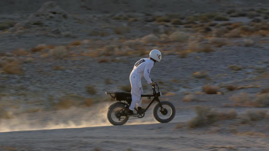 A man riding a dirtbike outdoors in the desert