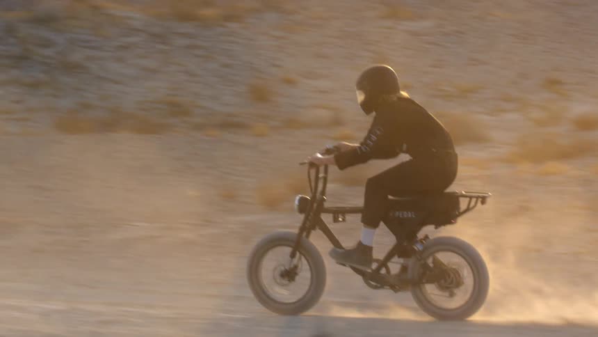 A teenager rides a dirt bike through the desert