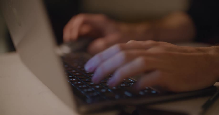 A person is typing on a laptop and moving the mouse