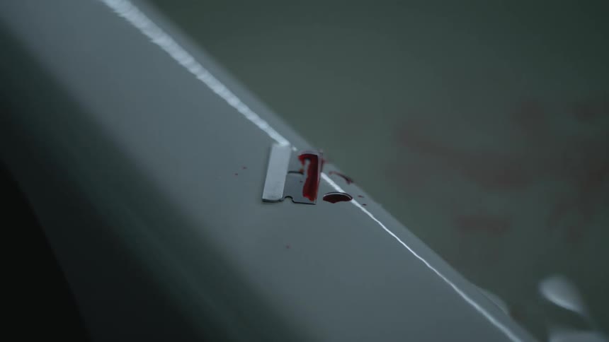 Bloody razor on bathtub in bathroom
