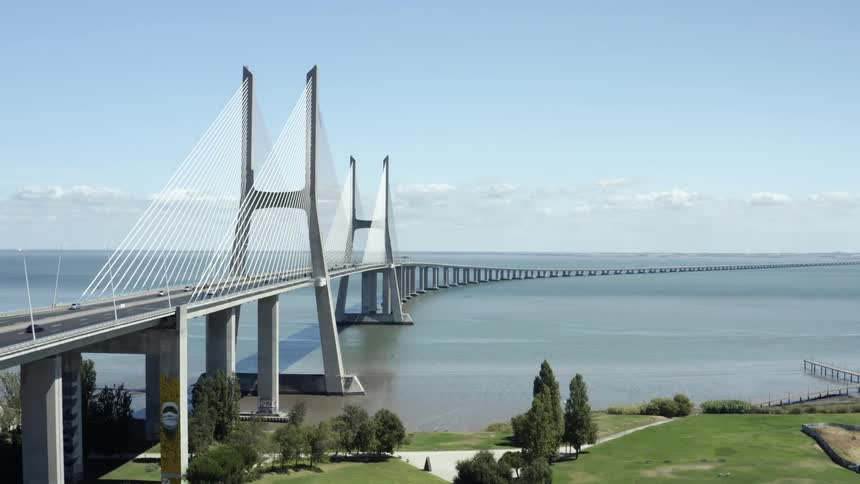 Cars are traveling over a large bridge over an ocean bay on sunny day
