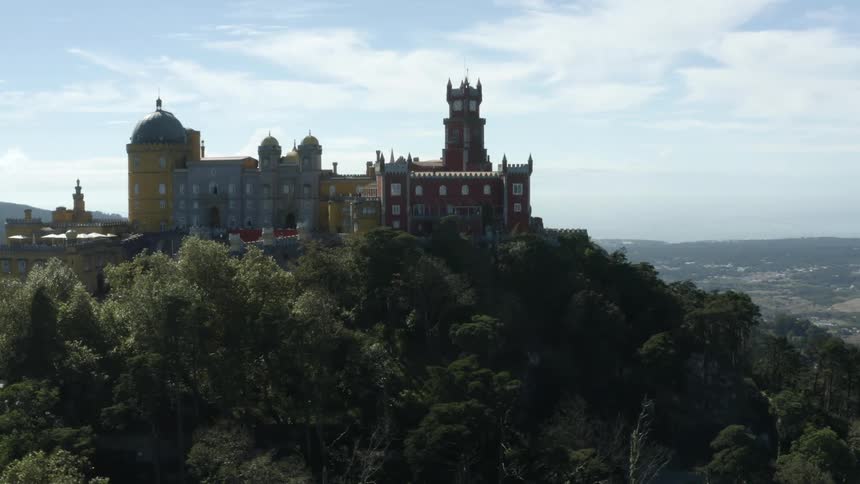 An aerial view of a castle on a hill with a town in the valley in the background during the day