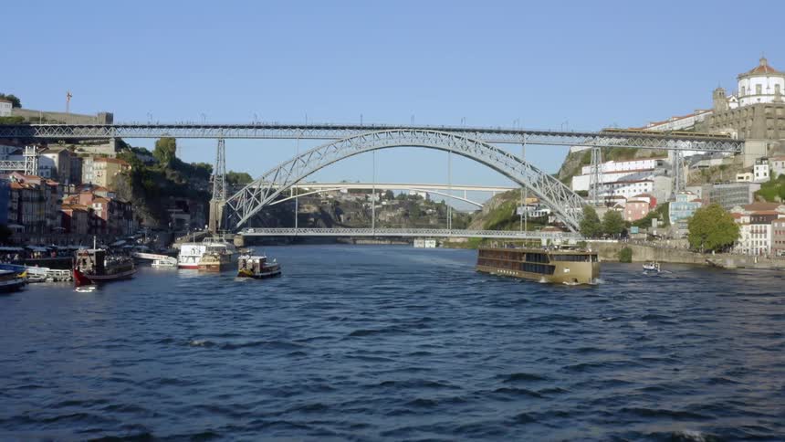 View of arch bridge over river with boats traveling