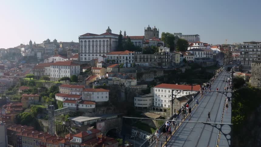 People walk across a bridge in front of buildings in a city