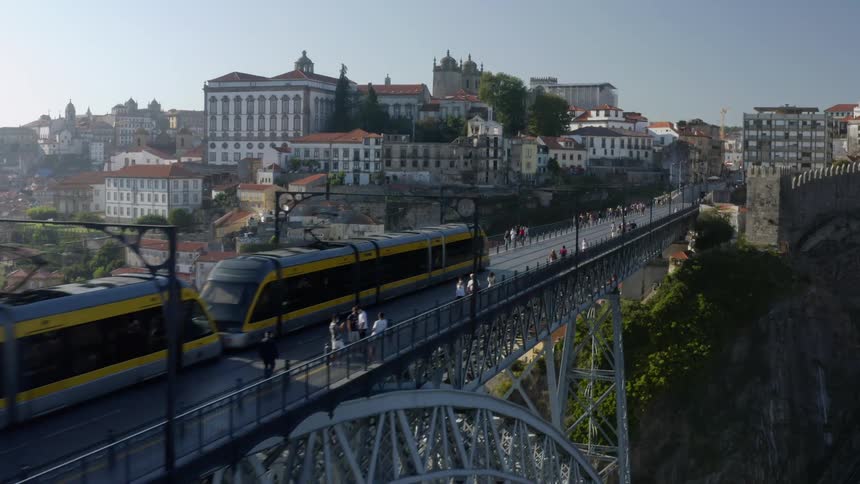 Pedestrians walk across a bridge in a city as a train drives down it