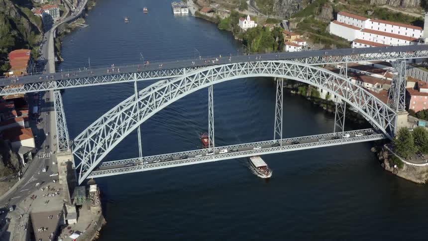 A tall bridge spanning a river in a city during the day