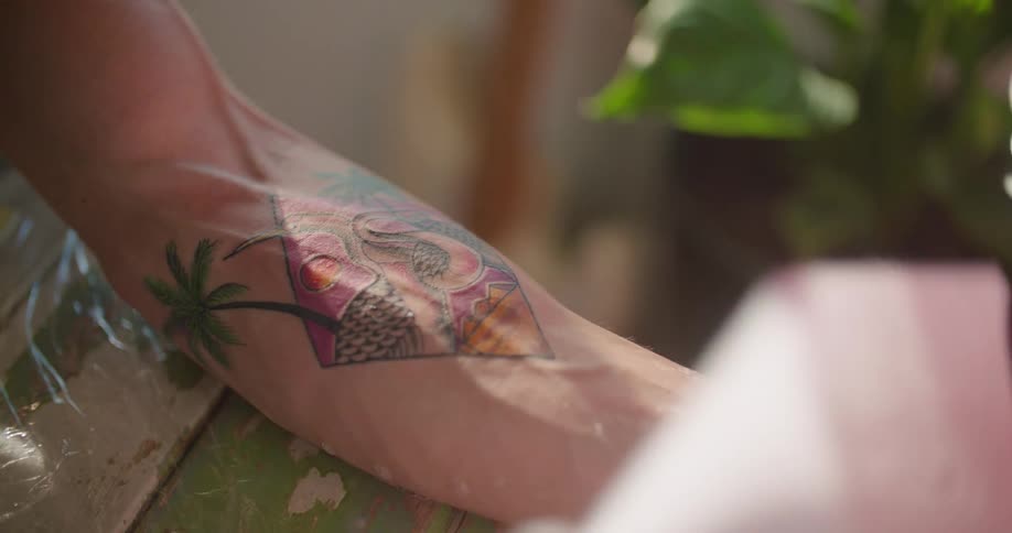 A tattoo artist uncovers the tattoo on the arm of a customer and wipes it clean