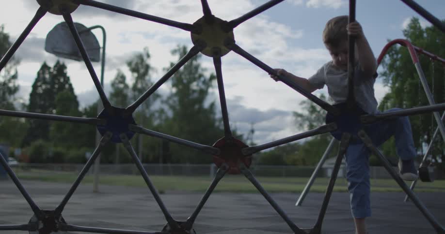 A boy is climbing on a jungle gym