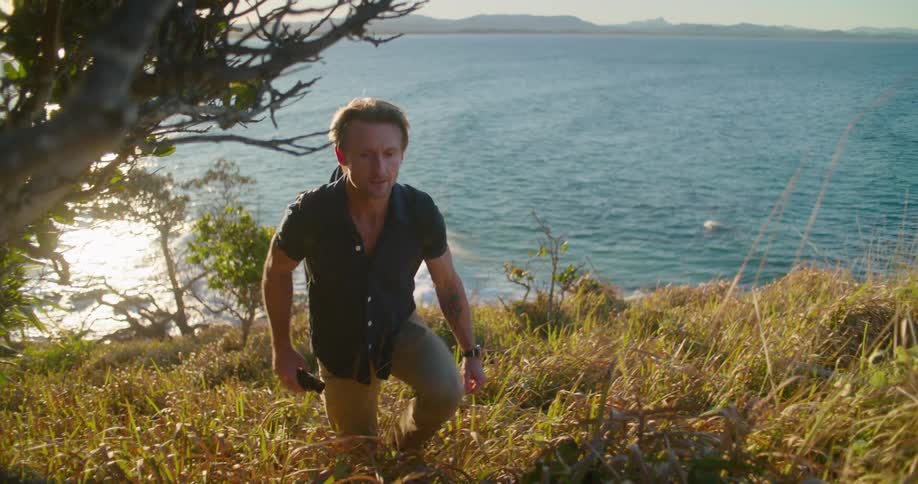 A man hikes up a hill along the coast