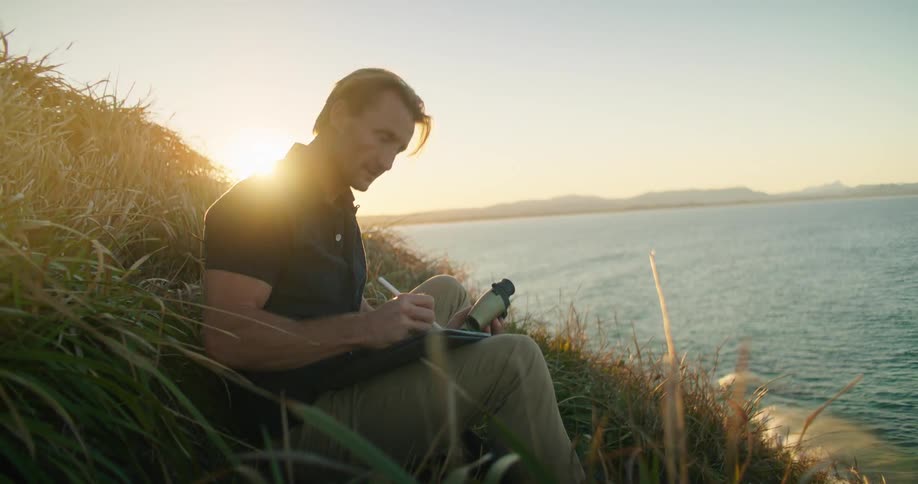 A man using binoculars and writing notes