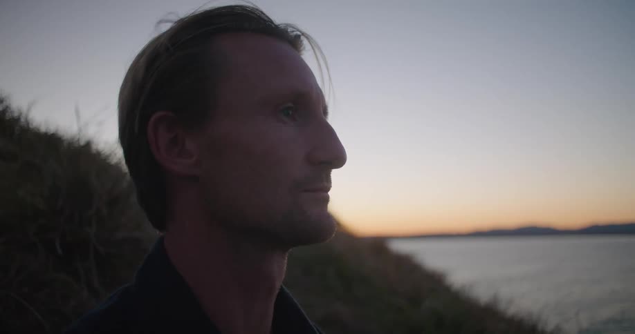 A man sitting and looking out at dusk