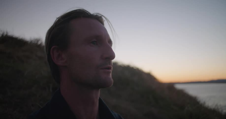 A man stands looking over a body of water