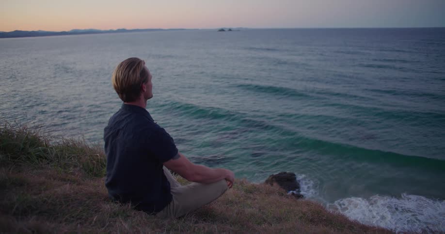 A man looking out to the ocean at dusk