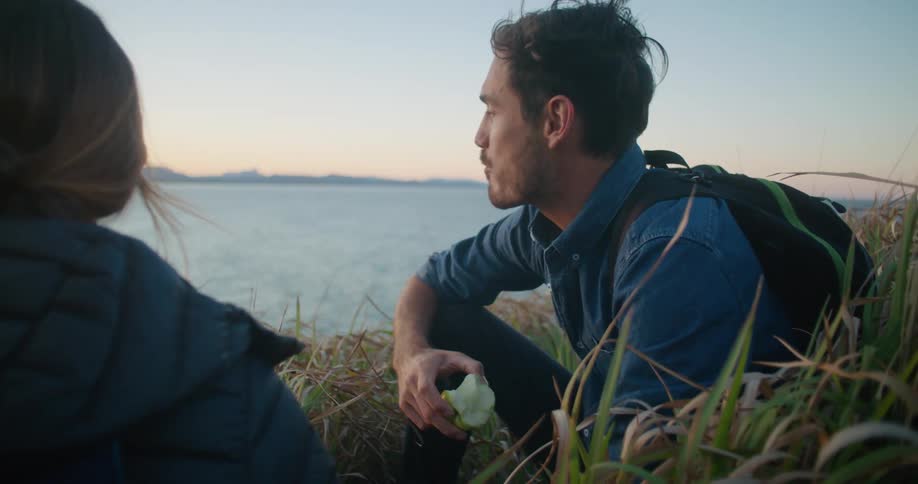 Two people sharing an apple by the ocean