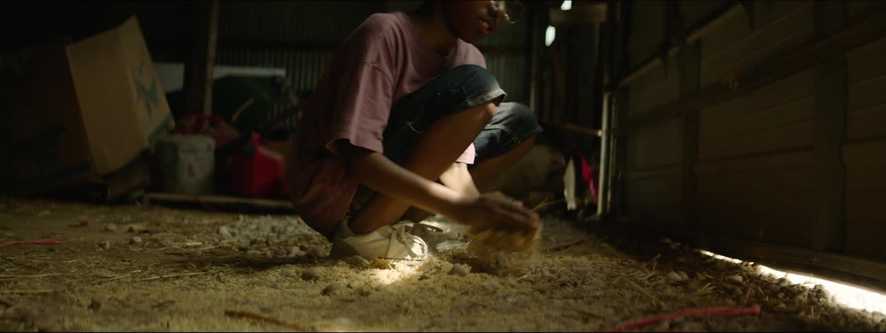 A young boy is scooping up sawdust from garage floor and throwing it into the air