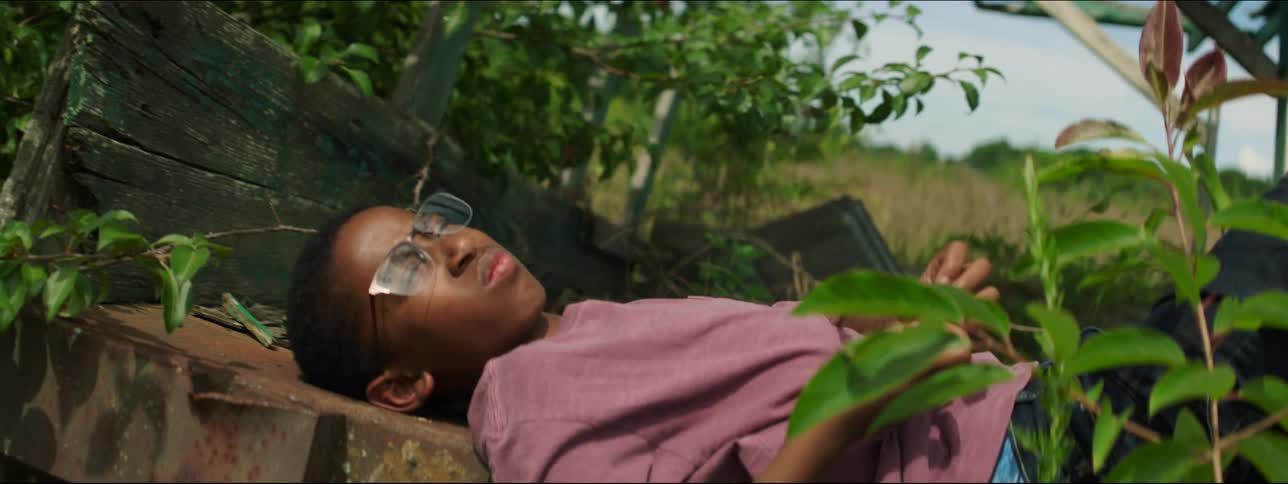 A boy is laying down outside on a sunny day