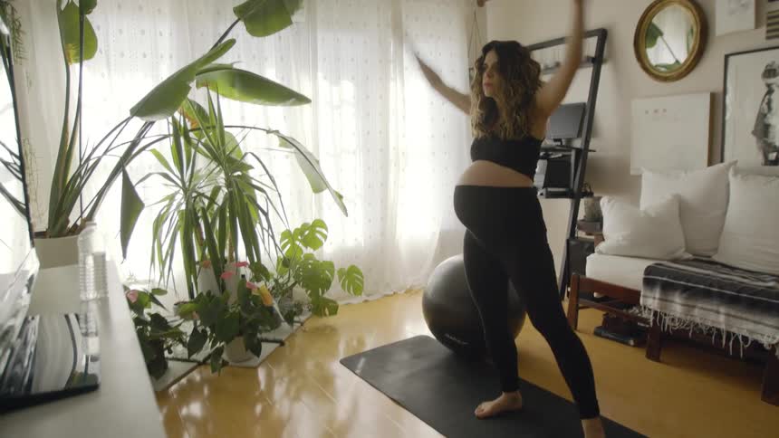 Pregnant woman exercises on yoga mat in living room