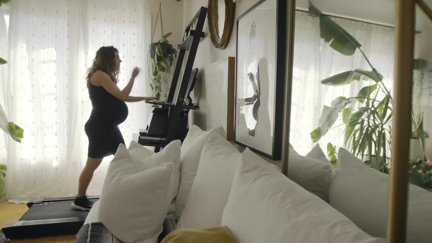 A woman walks on a treadmill while using a computer