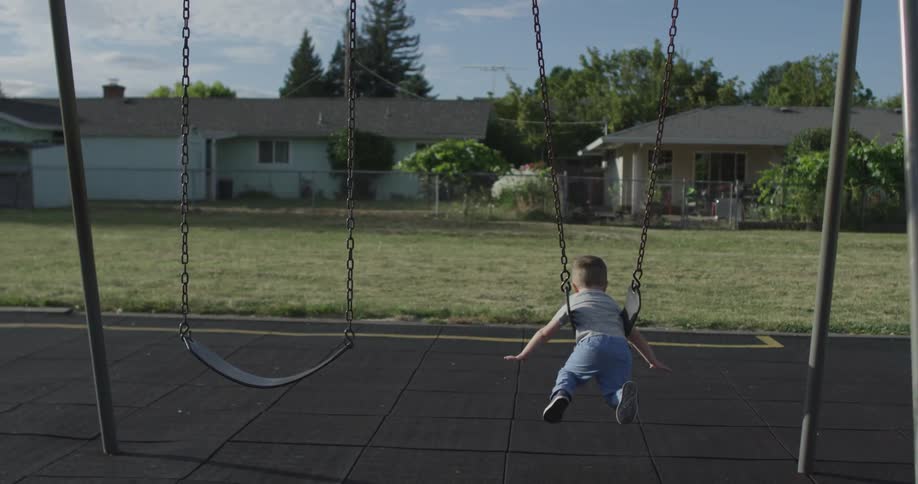A boy rides a swing in a playground