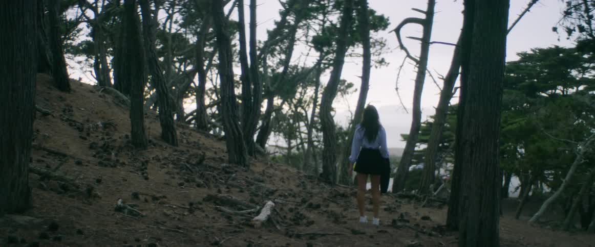 Woman with white shirt black shorts and white shoes wanders around in the forest