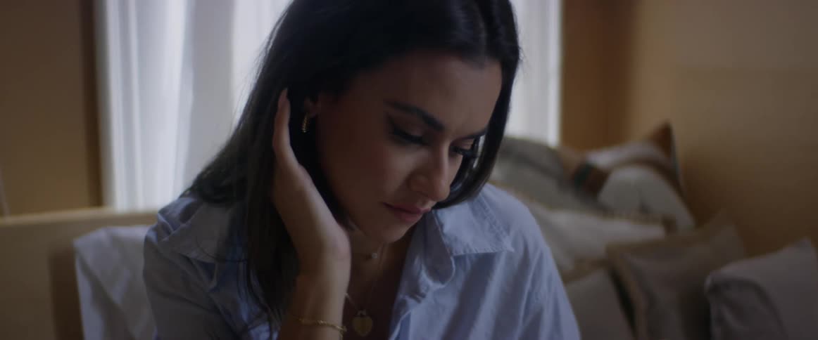 A woman is sitting on a bed while opening a book in the daytime