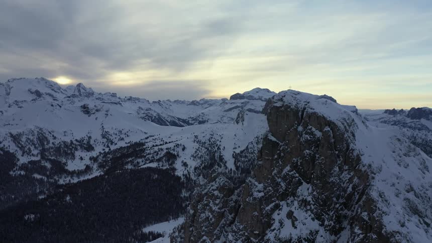 A mountain range covered in snow and ice with the sky and clouds in the background