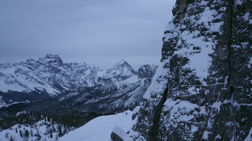 Snow covered mountains and forest trees in the wilderness on cloudy evening