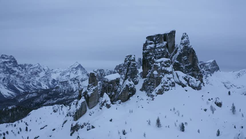 Aerial view of jagged rock formations rising over the snow in the mountains