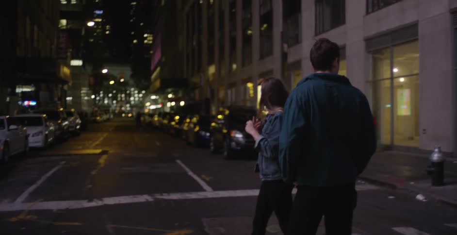 A man and woman walking down a road at night