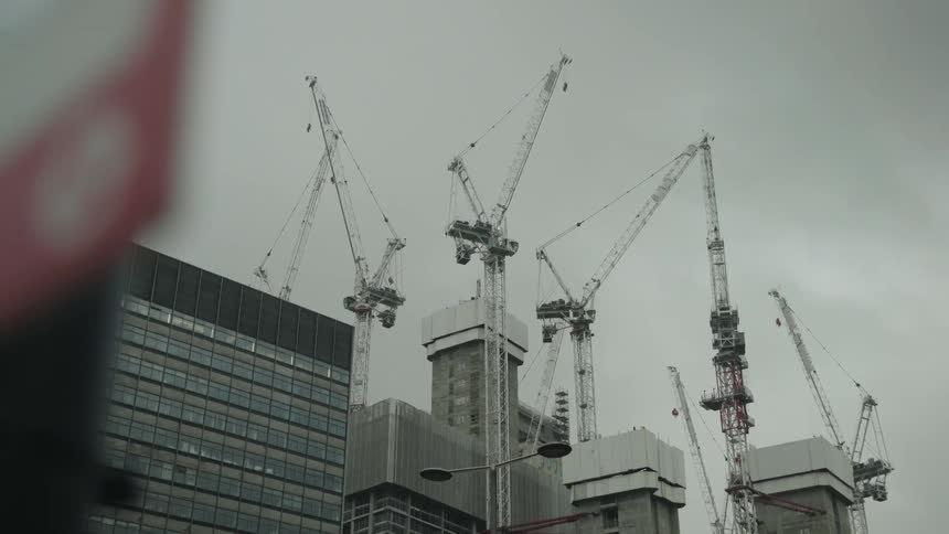 Construction cranes next to high rise office buildings in a city