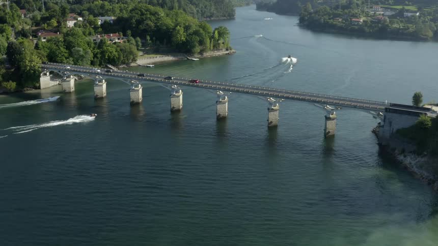 Cars are traveling over two bridges over a river waterway while boats travel under them