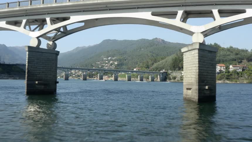 Boats travel in the river as cars drive over the bridge