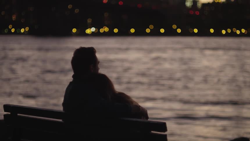 A couple sitting on a bench near a river