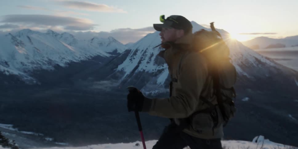 Man wearing winter clothes and a backpack hiking over the mountains at winter