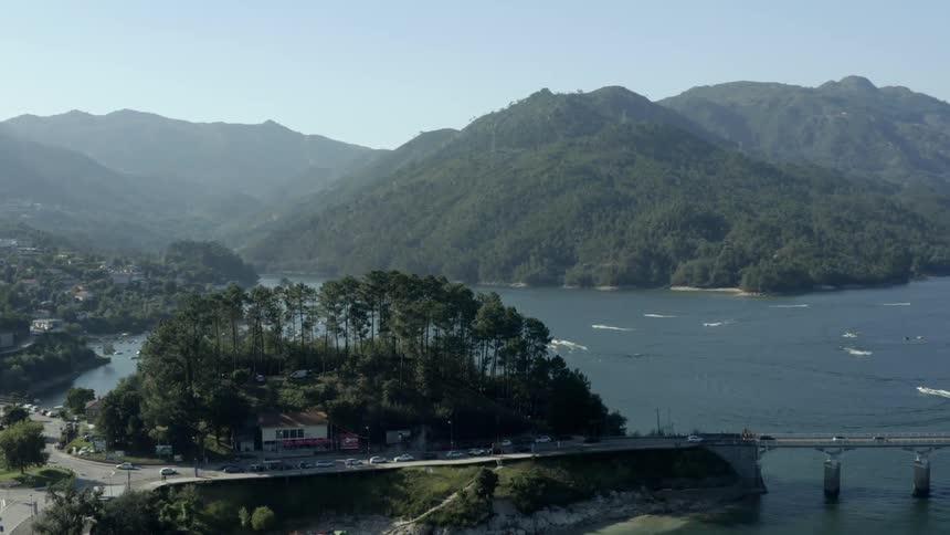 Aerial view of a bridge over a river next to a small town in the mountains
