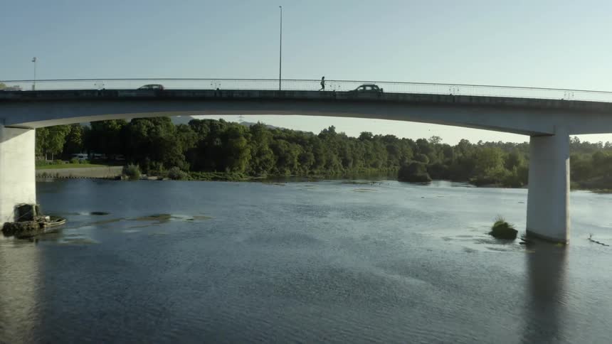 Aerial view of cars driving over small bridge next to forest