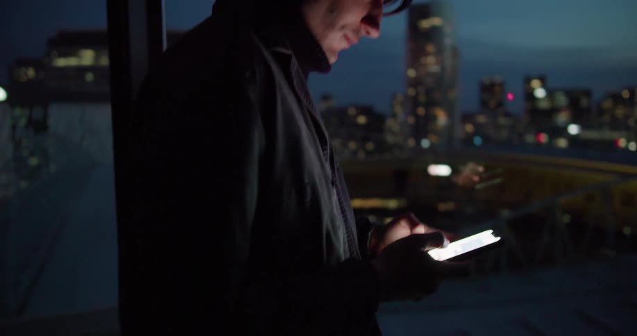 A man is using his cell phone by the window