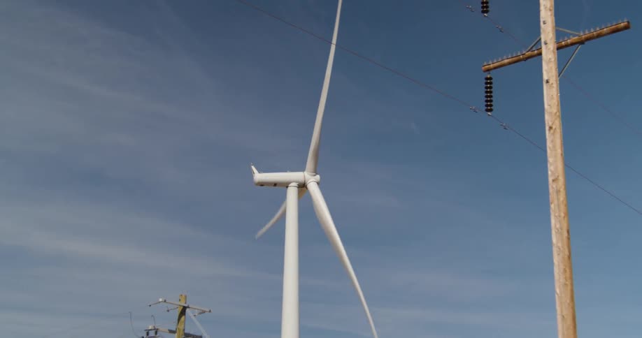 A windmill is spinning near a power line
