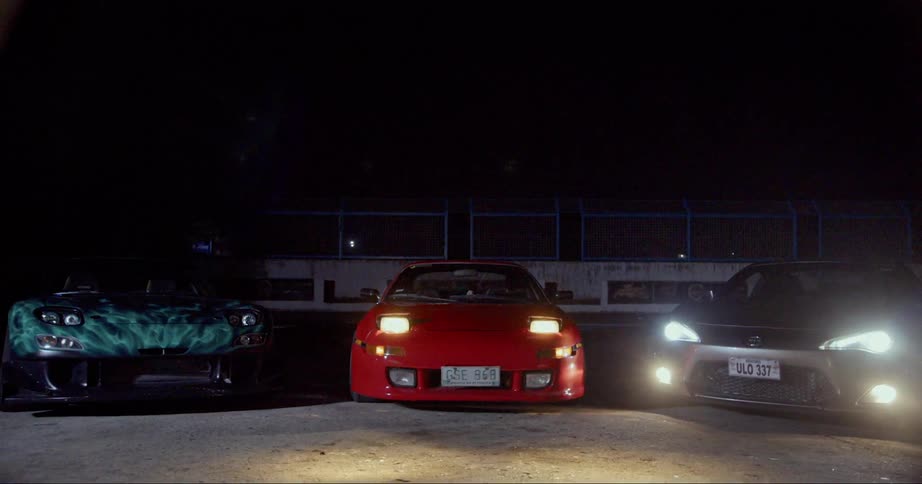 Three race cars are parked together at night