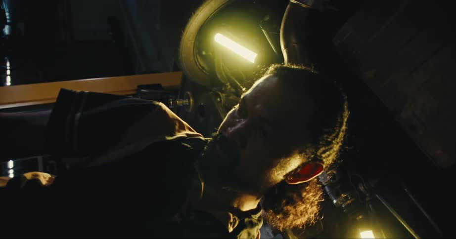 A mechanic picks up a tool under a car