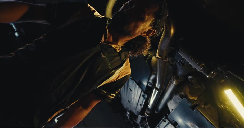 A mechanic standing under a vehicle
