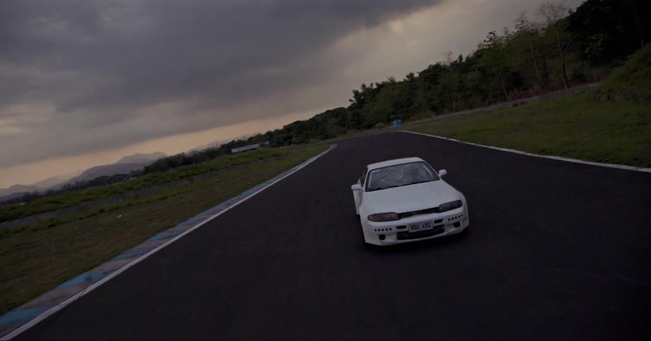 A car being driven around a race track on a cloudy evening
